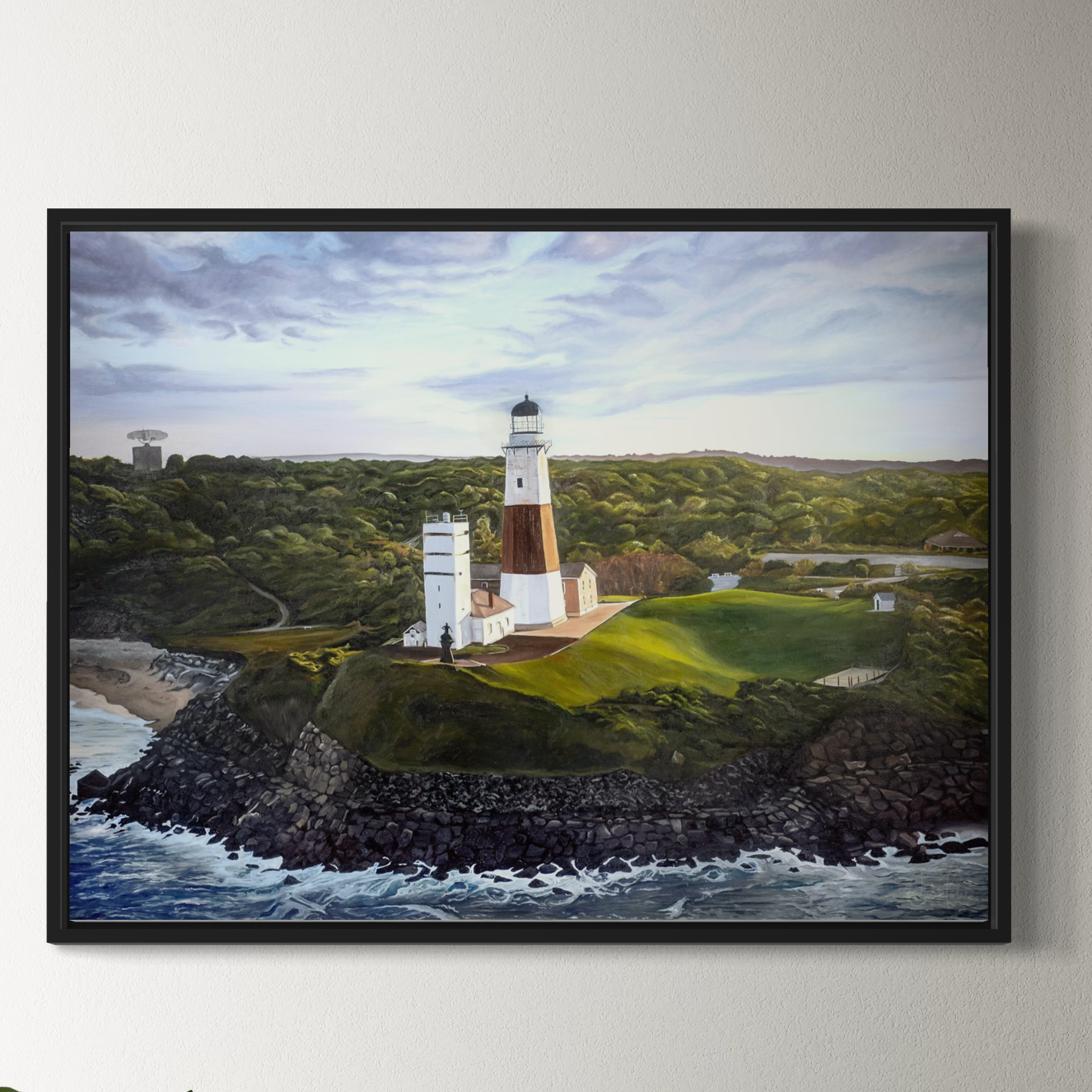 Framed painting of a lighthouse on a hillside with ocean view