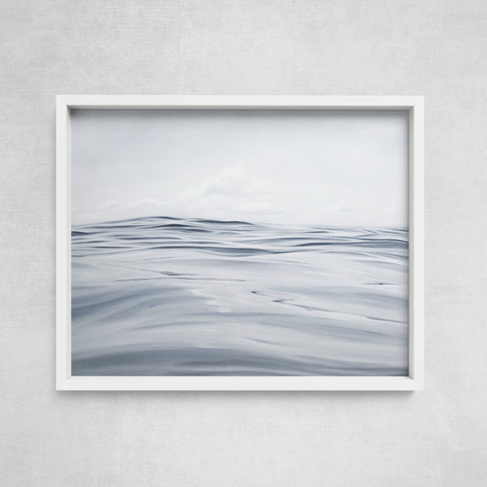A framed print depicting a serene open sea scene with gentle waves and a calm horizon.
