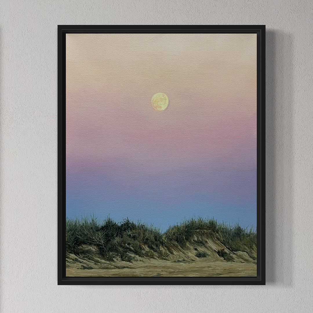 Framed artwork of a moonlit landscape with grassy dunes on a white wall.