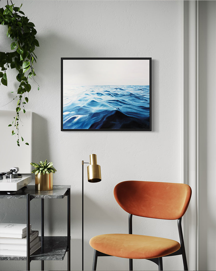 Modern interior with a framed artwork of water, orange chair, and side table.