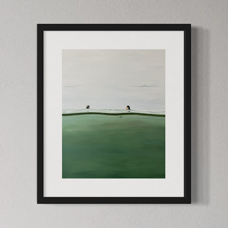 Framed artwork of a landscape with a green field and white sky on a gray wall.