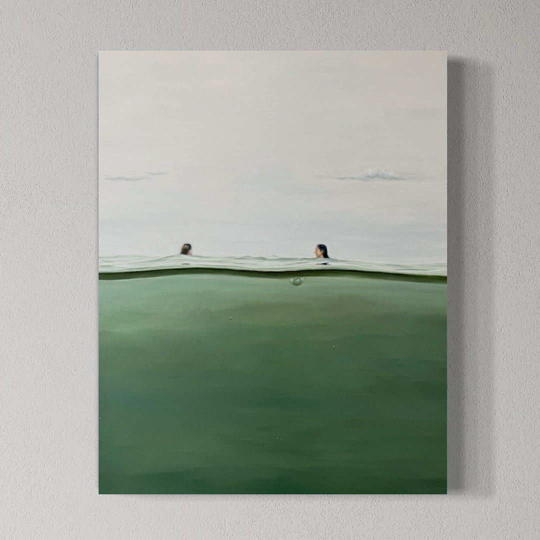Two people peeking over a green body of water with a white sky.