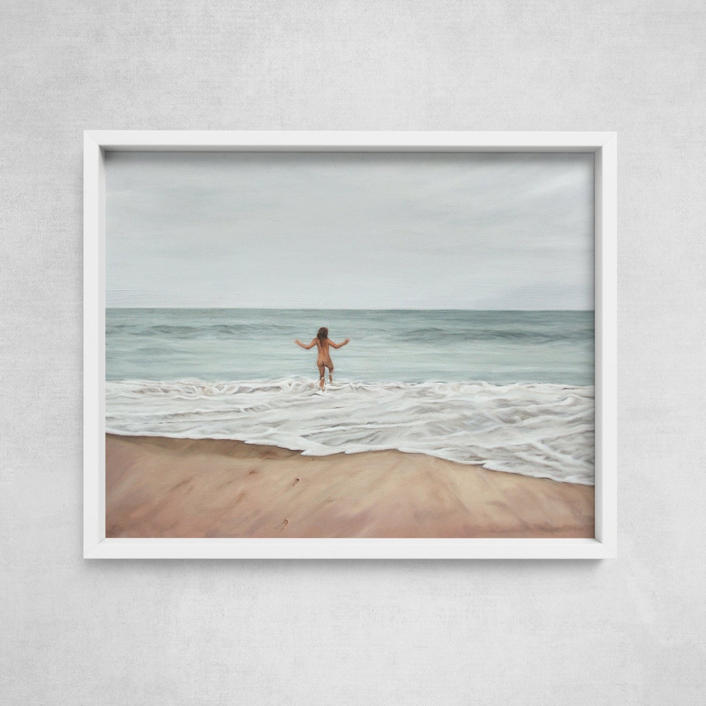 A framed art print depicting a nude figure standing on a beach with arms raised, facing the ocean.