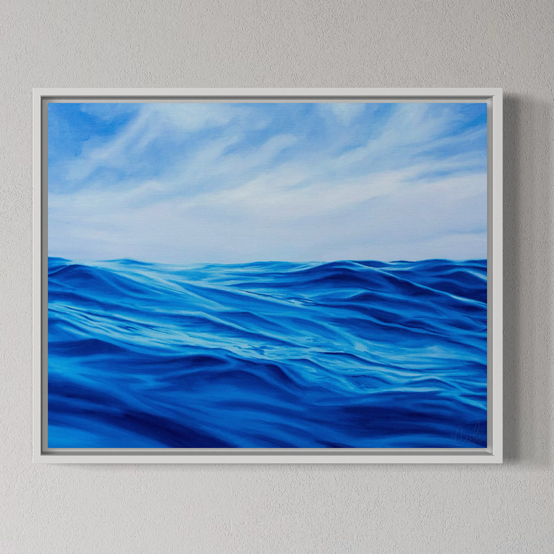 Framed artwork of blue ocean waves and sky on a gray wall