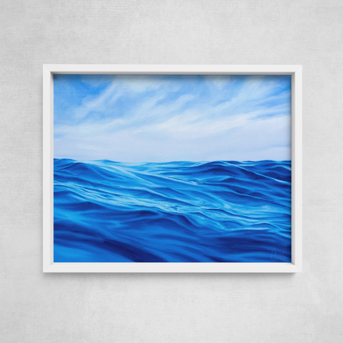 A framed fine art paper print depicting a painting of rolling ocean waves under a blue sky, displayed on a wall.