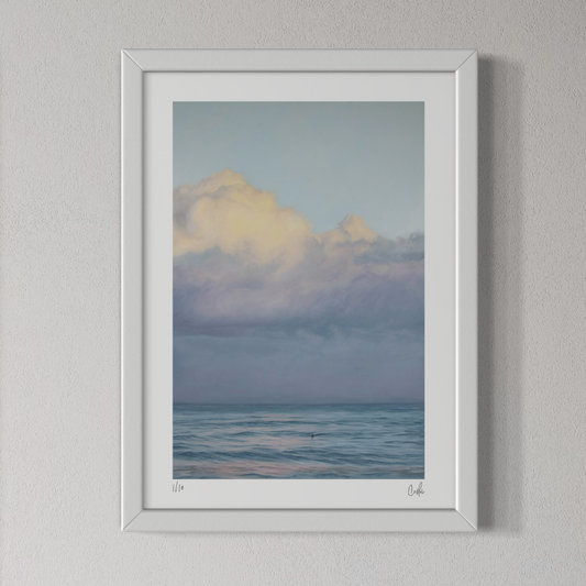 Framed artwork of a landscape with clouds and water on a gray wall