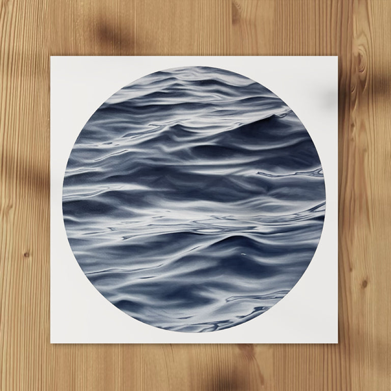 Circular artwork of wavy water on a white background, placed on a wooden surface.