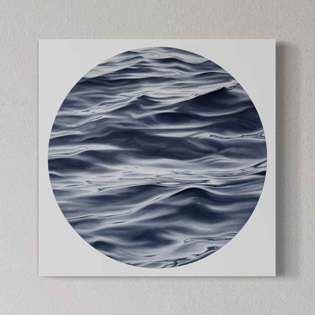 A framed fine art print of the ocean with a predominantly blue and white color palette, displayed on a wall.