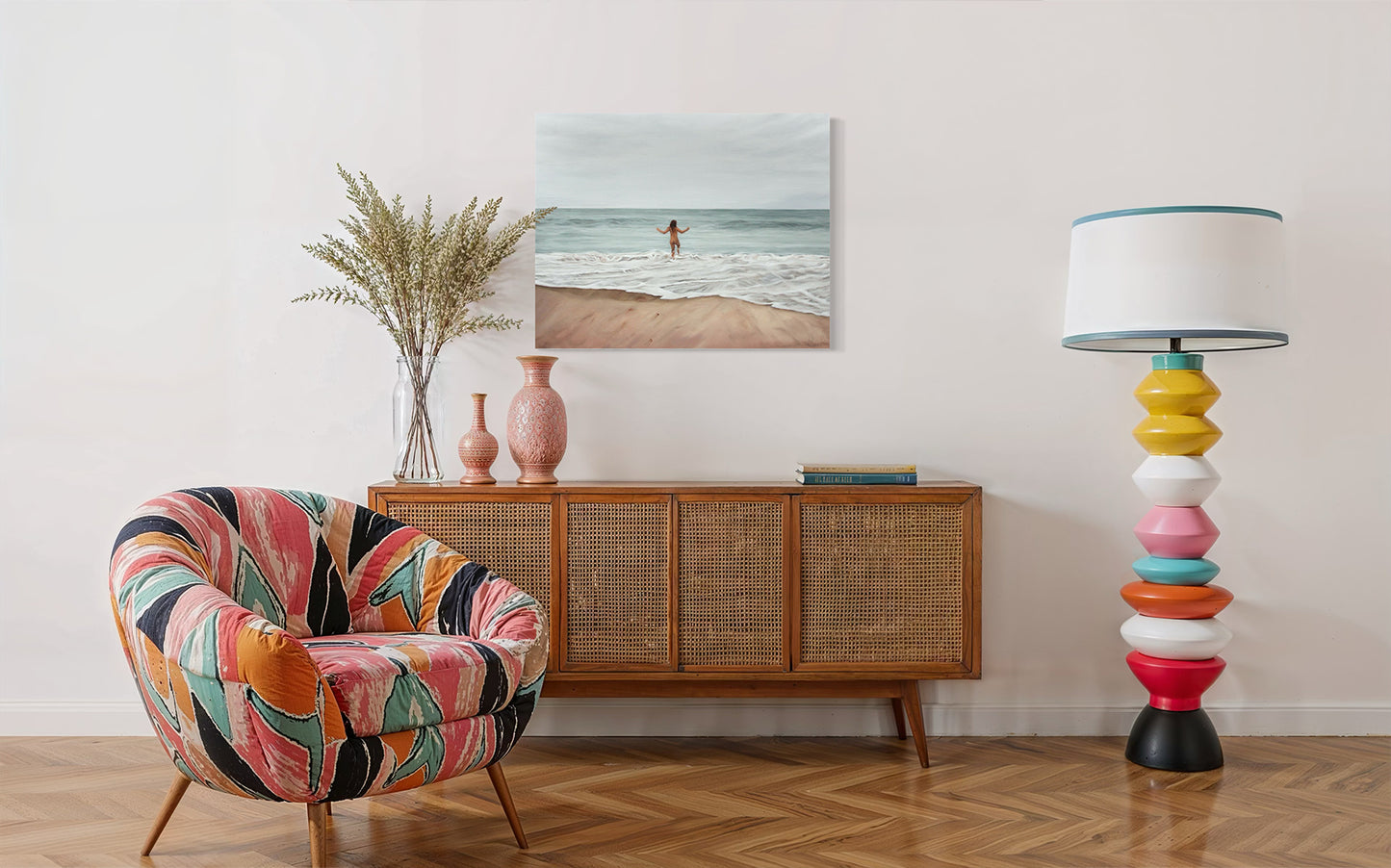 Colorful armchair in a room with a wooden sideboard, lamp, and beach-themed artwork.