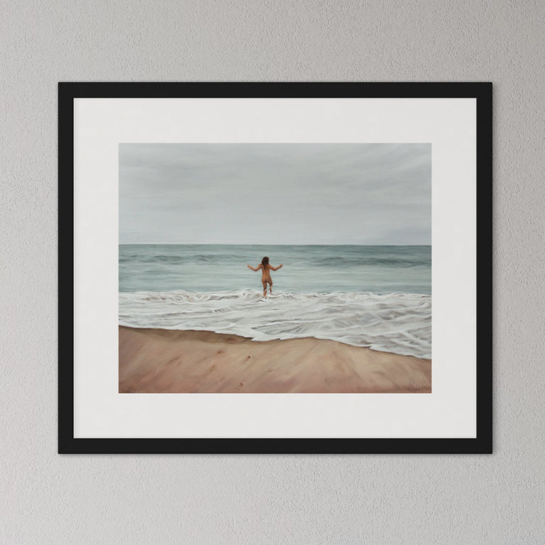 Framed artwork of a person walking on a beach with ocean waves.
