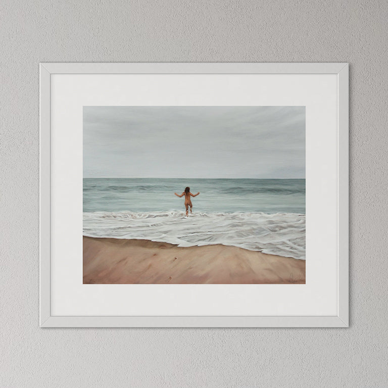 Framed artwork of a person standing on a beach with ocean waves.