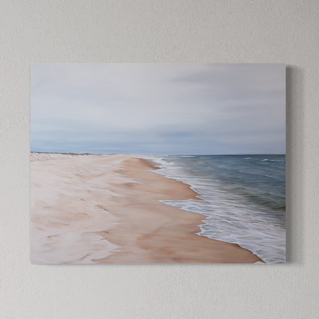 Canvas print of a beach scene with sand and ocean on a wall.