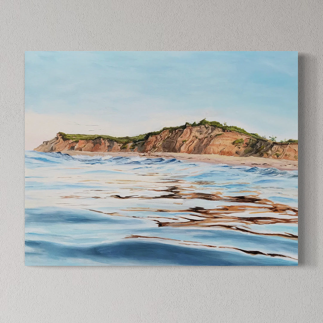 Canvas print of a coastal landscape with cliffs and water on a gray wall.