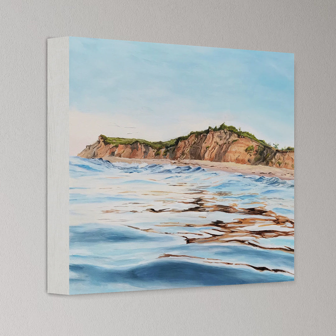 Canvas print of a coastal landscape with cliffs and ocean waves on a gray wall.