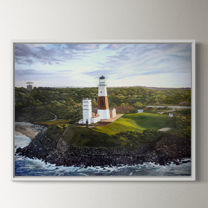 Framed painting of a lighthouse on a rocky outcrop with ocean and landscape in the background.