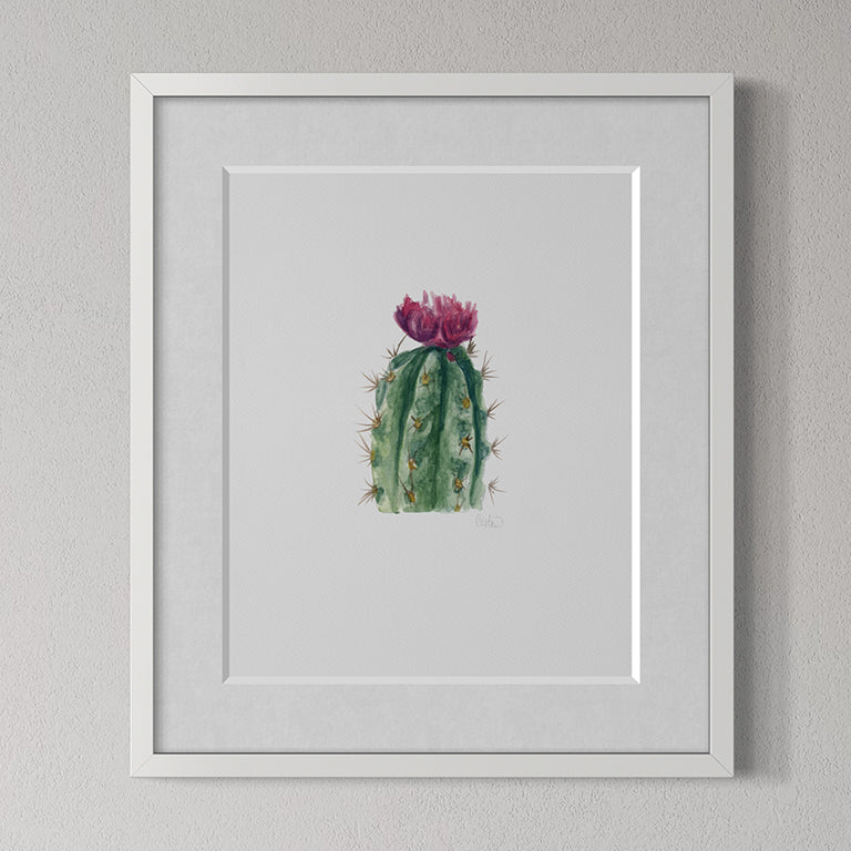 Framed artwork of a cactus with pink flowers on a gray wall