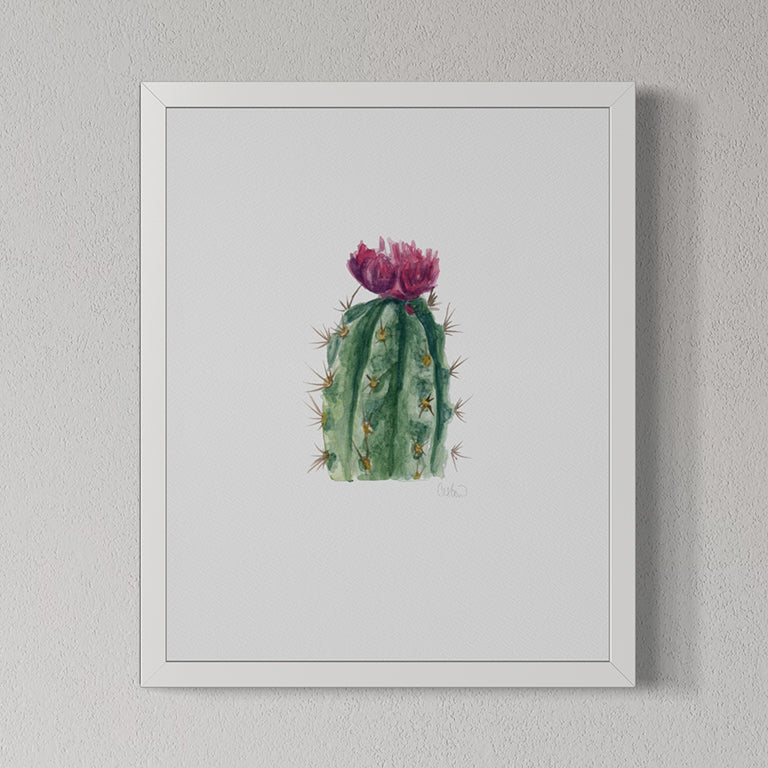 Framed artwork of a cactus with pink flower on a gray wall