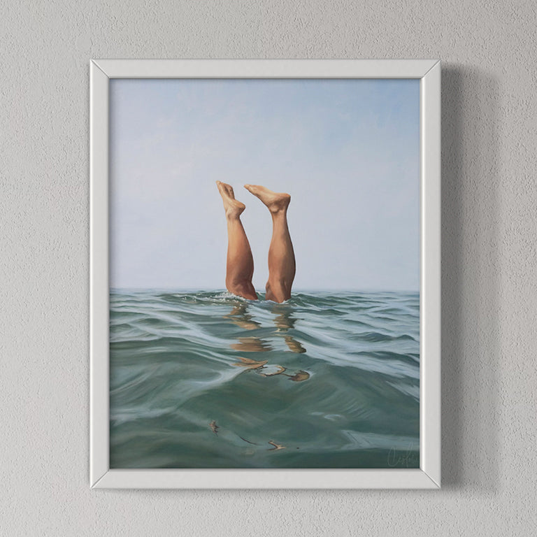 Framed artwork of legs diving into water with a white frame on a gray wall.