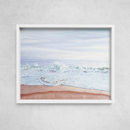 A framed print depicting a serene beach scene with a pastel-colored sunset and gentle waves.