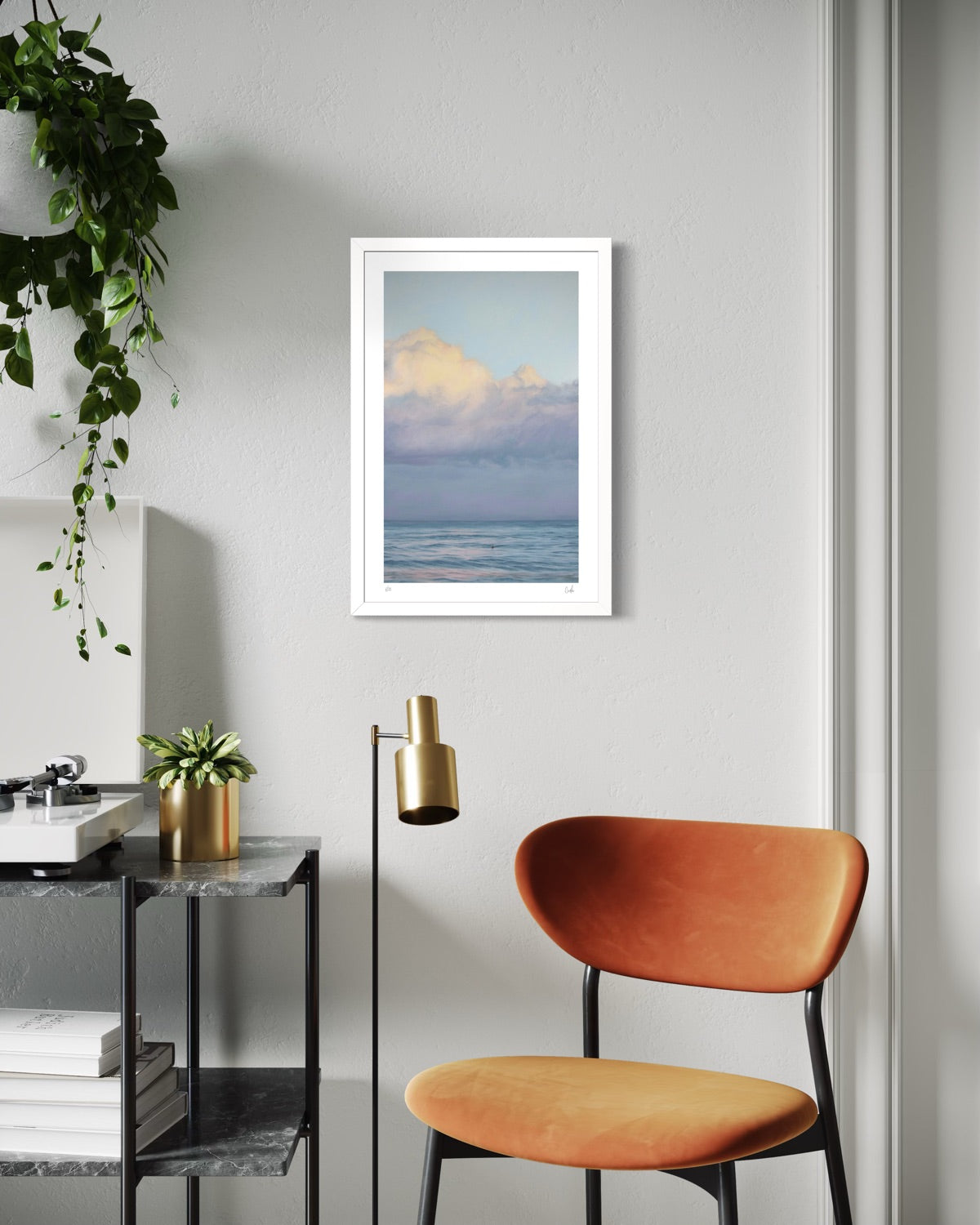 Modern interior with a framed artwork of a cloud over water, a brown chair, and a plant.