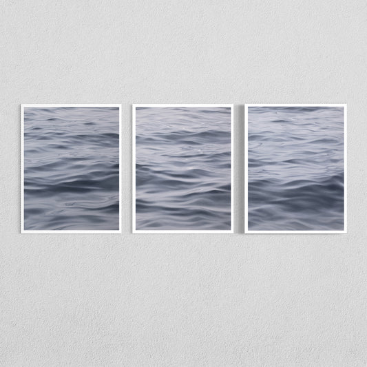 Three framed vertical art prints showing a close-up view of rippling water, arranged side by side on a light gray textured wall.