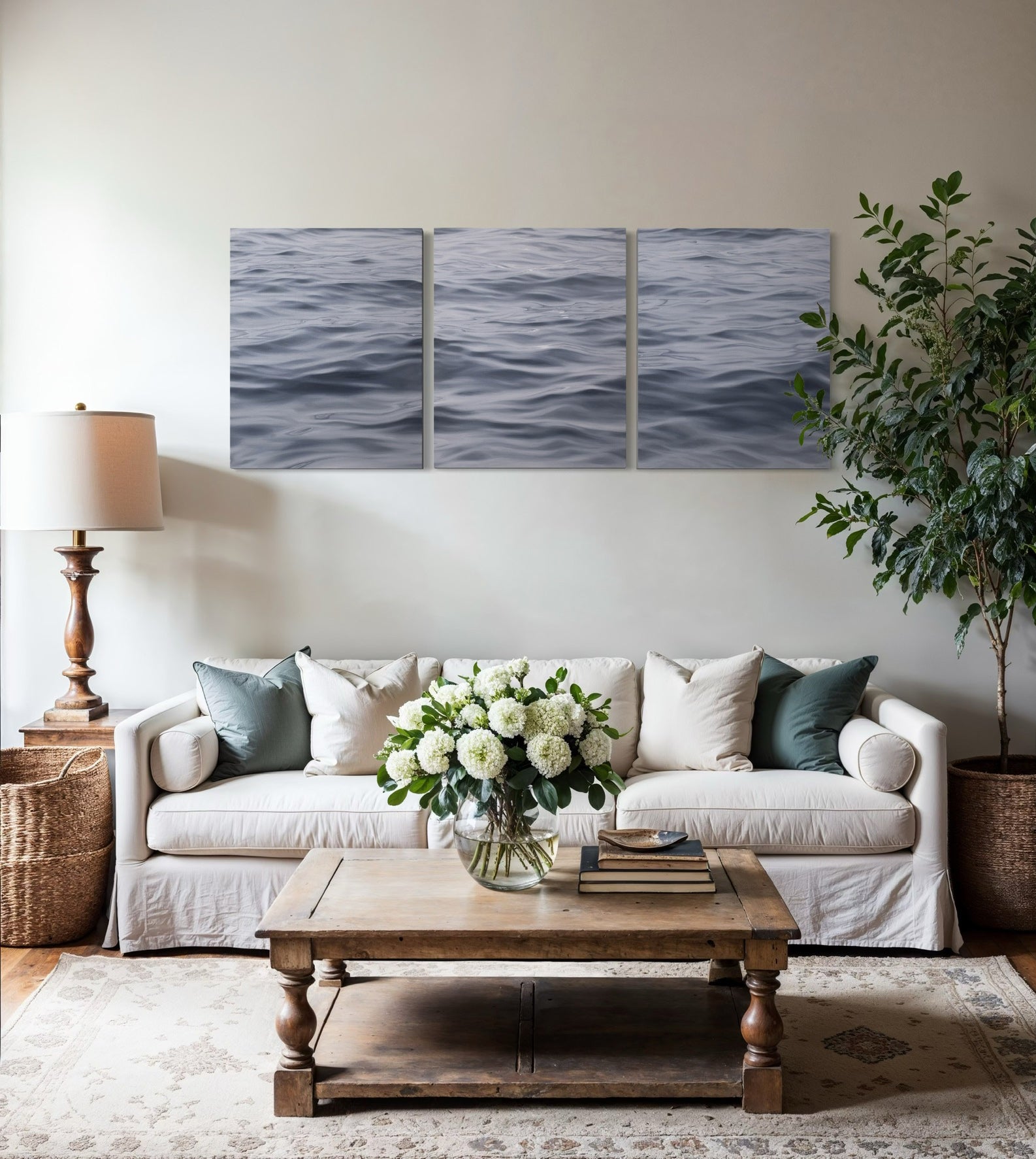 Large original triptych seascape oil painting displayed above sofa in neutral coastal living room interior.