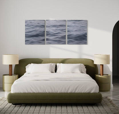 Large original triptych ocean painting above bed in modern bedroom with soft neutral decor.