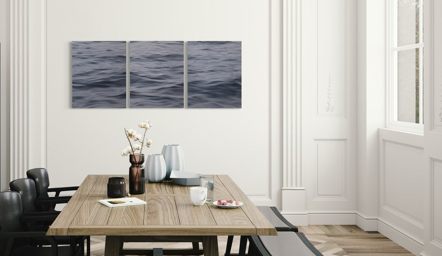 Contemporary seascape triptych painting displayed in light-filled dining room interior.