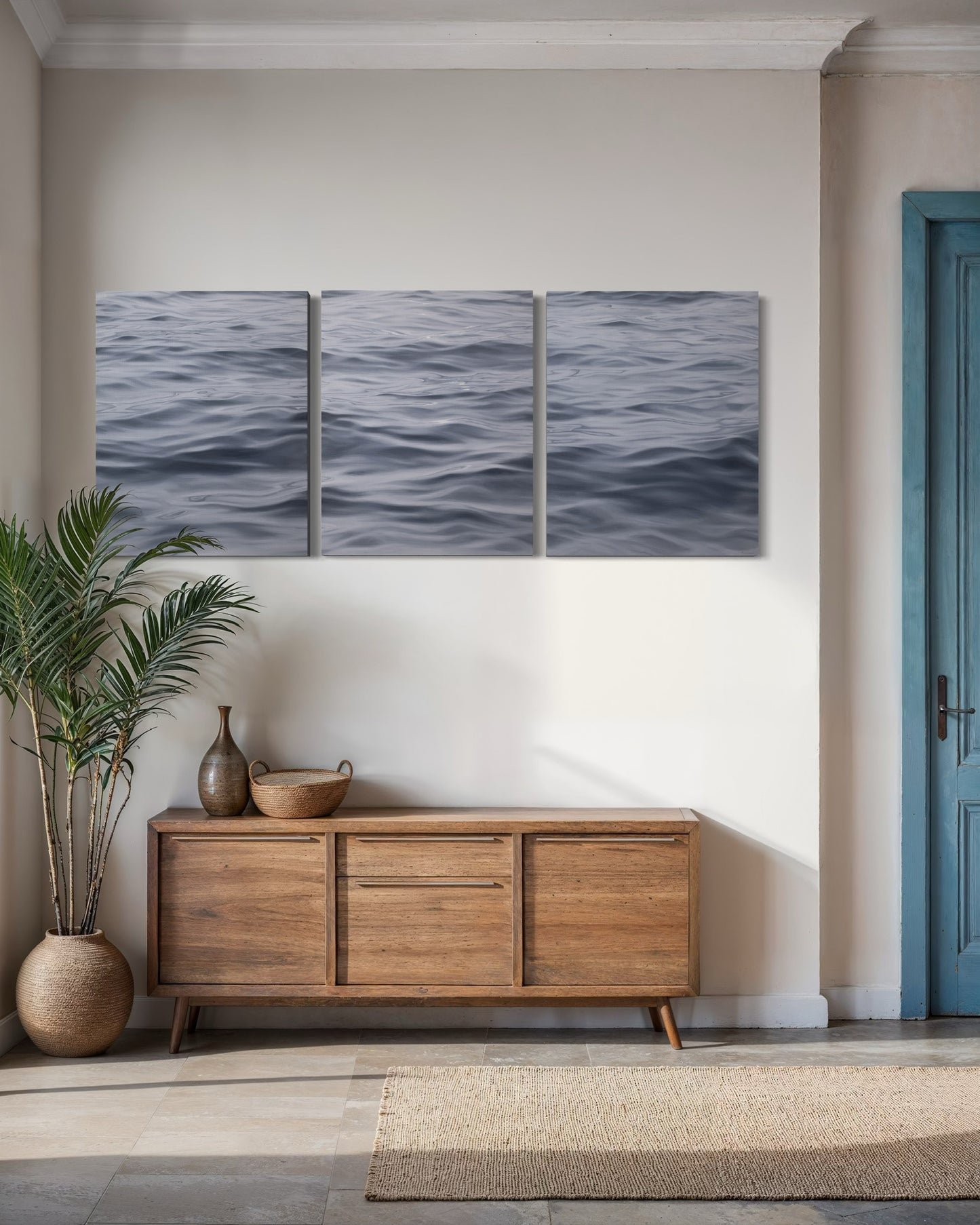 Original seascape triptych wall art above wooden console in contemporary coastal home interior.