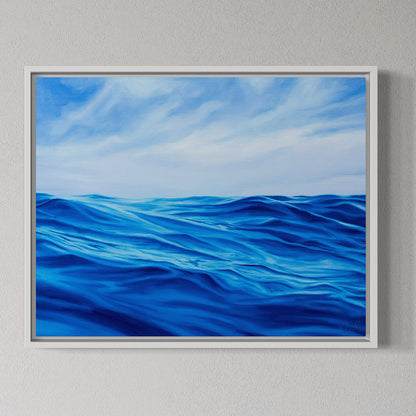 Framed artwork of blue ocean waves and sky on a gray wall