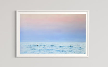 A framed limited edition fine art print titled 'Twilight Whispers' depicting a serene coastal scene with surfers and a pastel-colored sky.