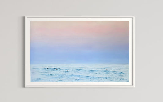 A framed limited edition fine art print titled 'Twilight Whispers' depicting a serene coastal scene with surfers and a pastel-colored sky.