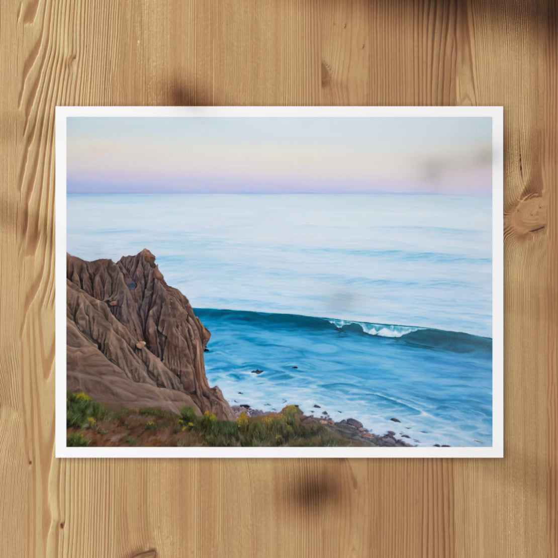 All We Have is Here fine art print of a coastal cliff and wave, laid flat on a wood surface