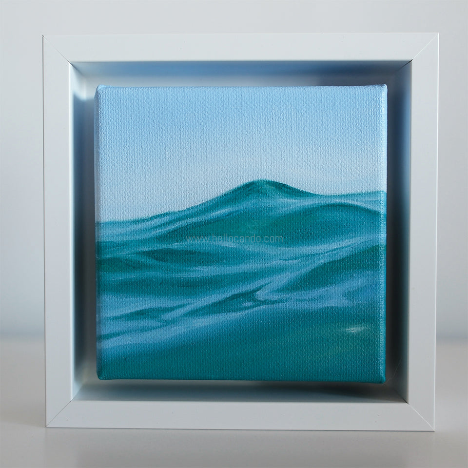 Mini #50 by Candace Ceslow displayed in white frame — minimalist coastal wave study in soft blue tones.