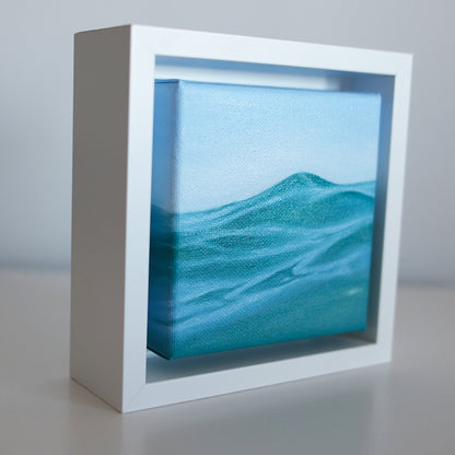 Side view of Mini #50 framed wave painting — textured teal water and rising swell in a modern white shadow box frame