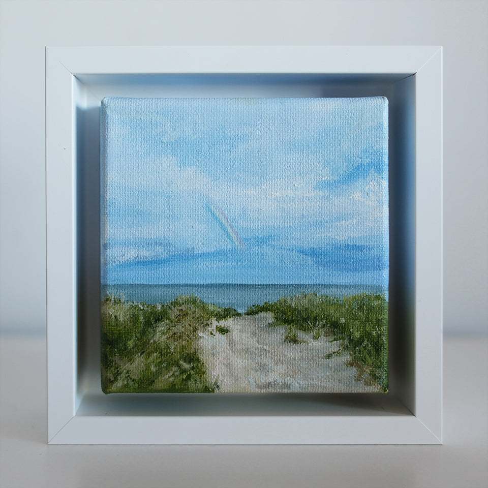 Front view of Mini #51 coastal path oil painting framed in white — beach grass, ocean, and soft rainbow in the distance.