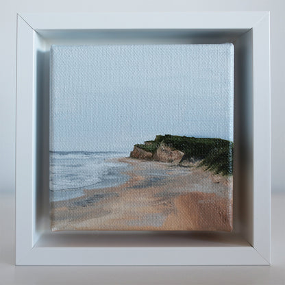 Small coastal cliff painting in white shadow box frame — Montauk beach scene by artist Candace Ceslow.