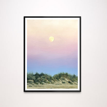 A framed landscape art print featuring a pastel sunset sky with a yellow moon over green beach dunes, displayed on a light gray wall.
