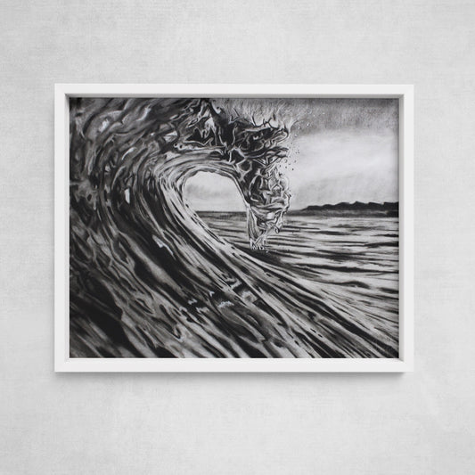 A framed black and white charcoal drawing of a breaking wave, displayed on a wall.