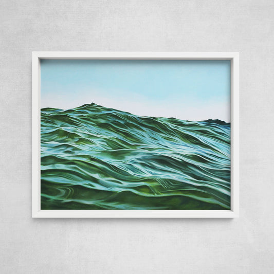 A framed fine art paper print depicting a seascape with ocean waves, hanging on a wall.