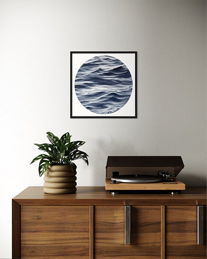 Wooden cabinet with a plant and record player, framed artwork above on a plain wall.