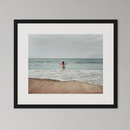 Framed artwork of a person walking on a beach with ocean waves.