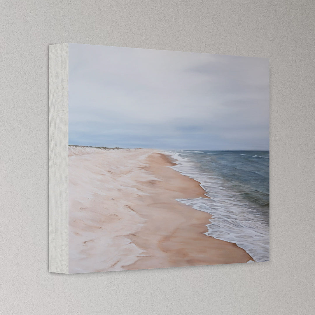 Canvas print of a beach scene with waves and sand on a light gray wall.