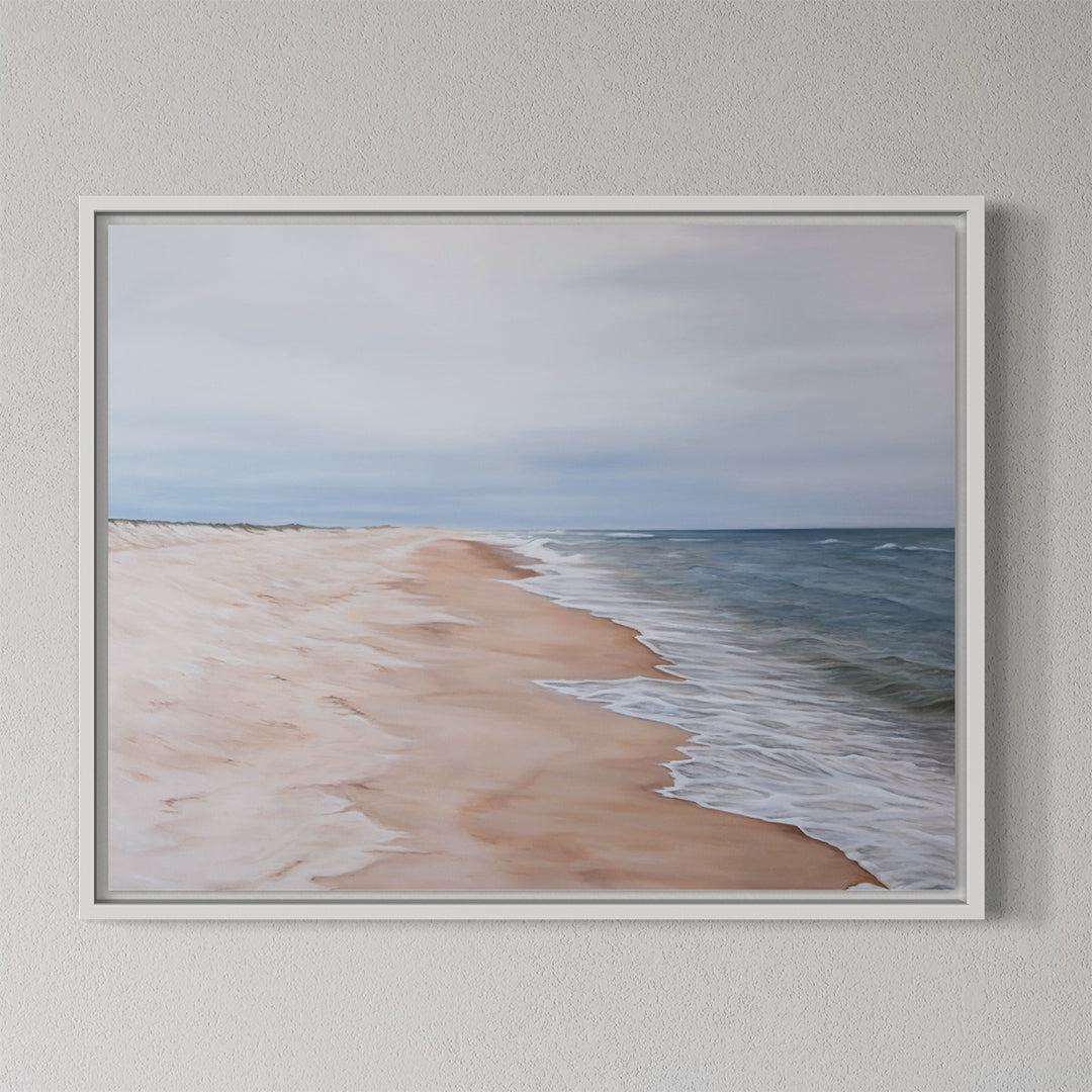 Framed artwork of a beach scene with ocean and sky on a gray wall.