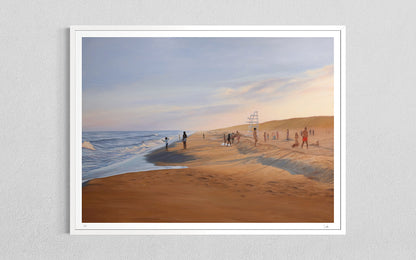 A framed art print depicting a beach scene with sand dunes, ocean waves, and small figures of people, mounted on a light gray textured wall.
