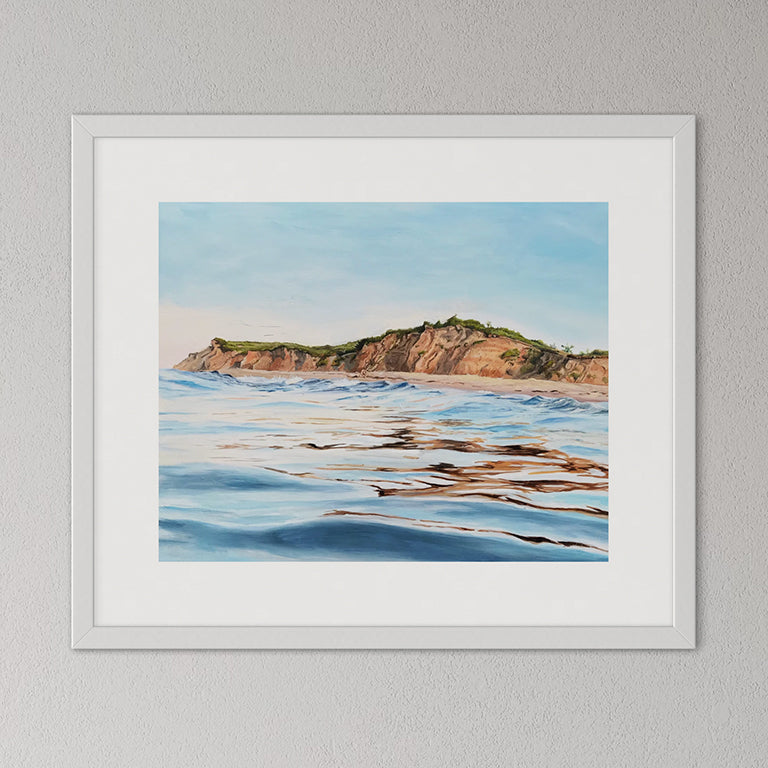 Framed artwork of a coastal scene with cliffs and water.