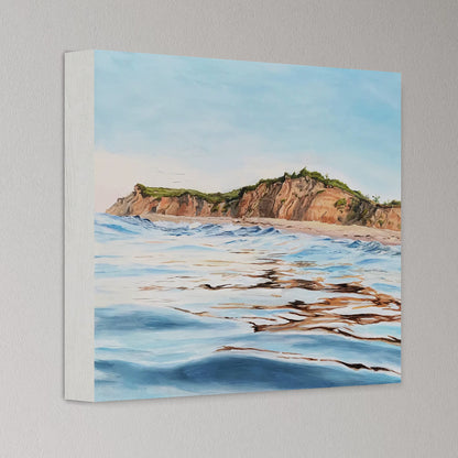 Canvas print of a coastal landscape with cliffs and ocean waves on a gray wall.